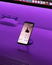 A sleek smartphone displaying the findhere app's live presence feature with glowing user icons on a dark purple background.