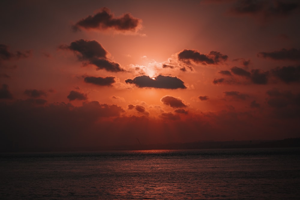 the sun is setting over the ocean on a cloudy day