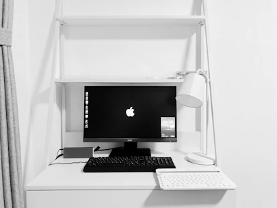 Minimalist workspace featuring black and white monitors displaying digital workflows.