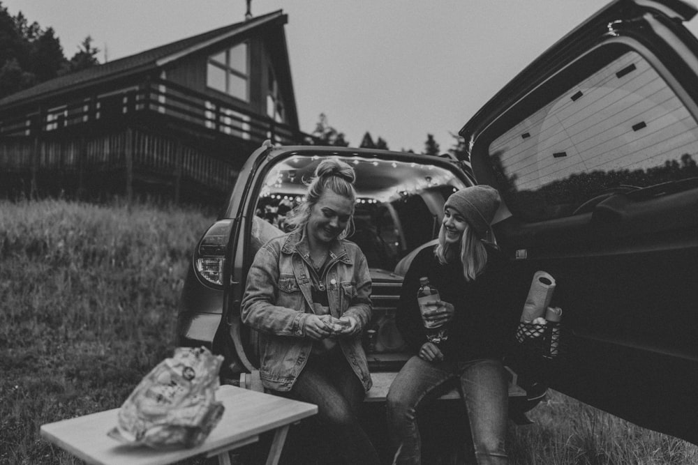 grayscale photo of women sitting on vehicle