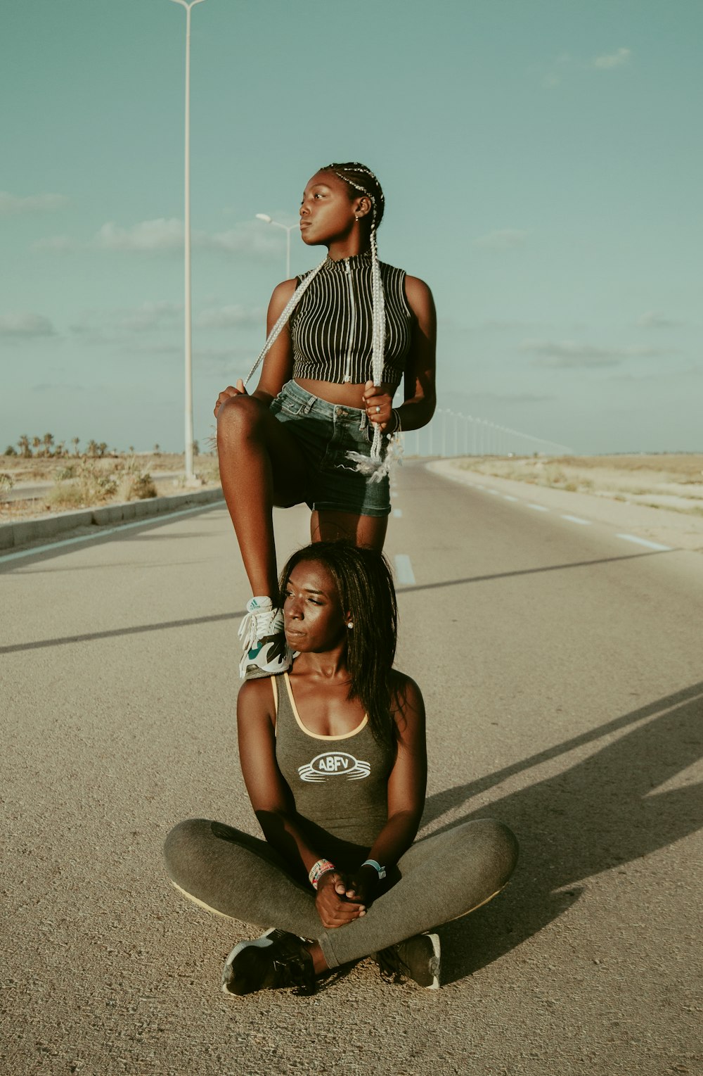 woman stepping on foot on another woman's shoulder while on road