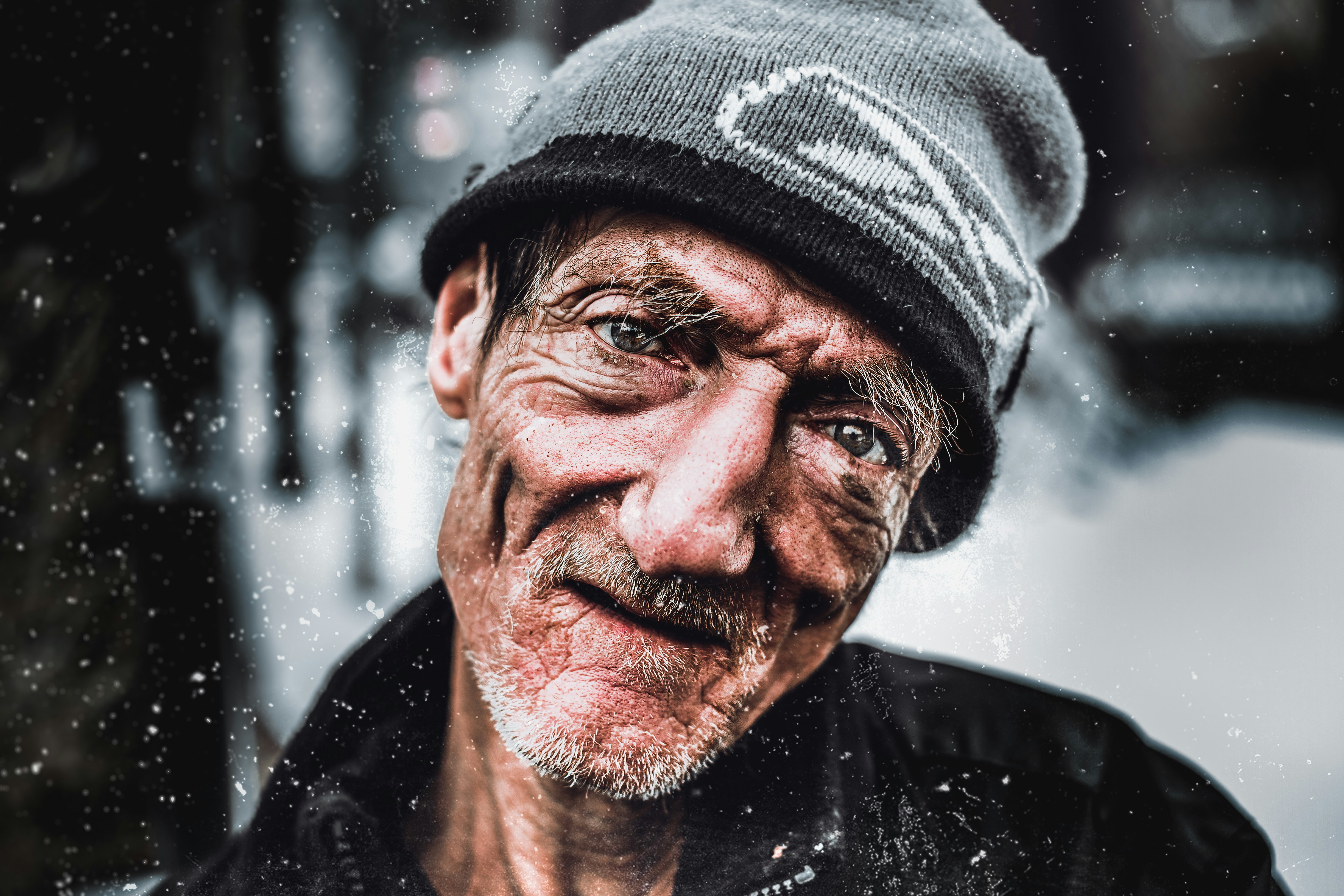 smiling man in black jacket and gray knit hat