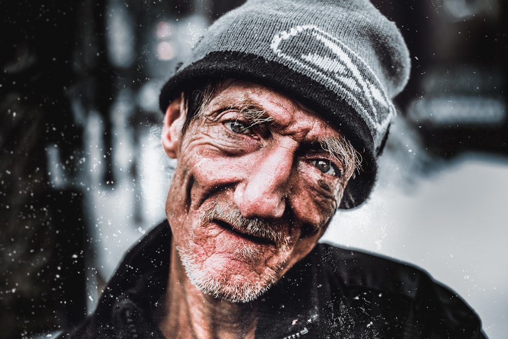 smiling man in black jacket and gray knit hat