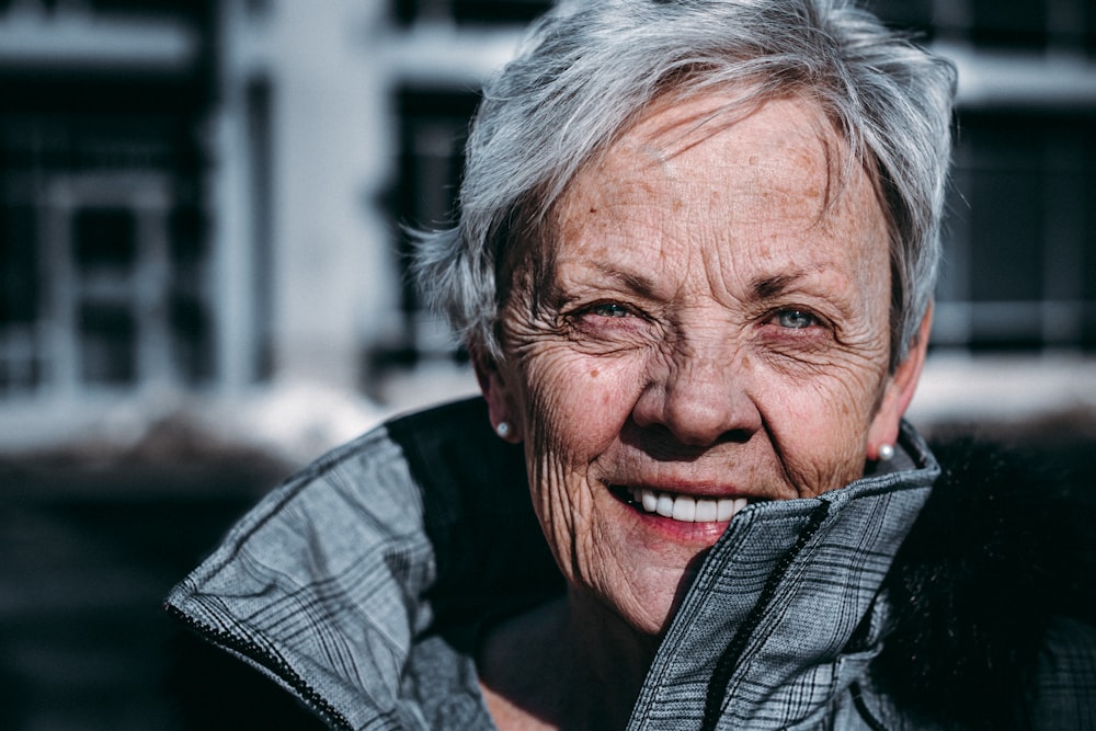 Woman with grey hair wearing grey coat and smiling