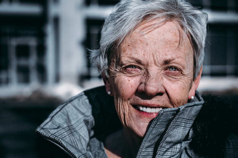 Elderly Indian mother smiling while using Carissa elder care app on smartphone