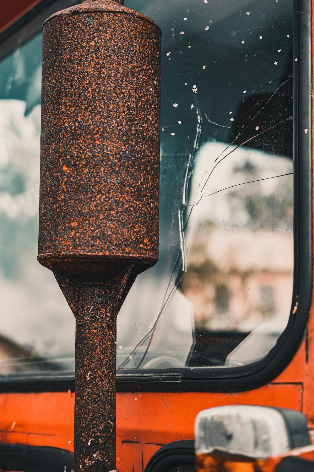 a rusted metal pole sitting next to a window