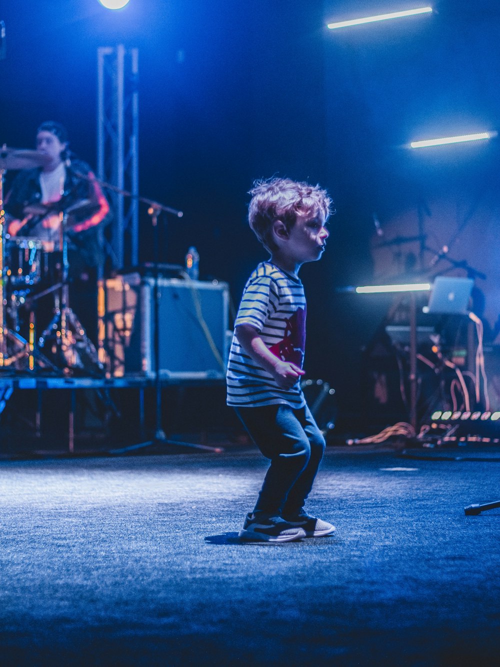 boy in striped shirt on stage with lights