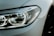 Close-up of a modern car's headlight showcasing sleek design and clear detailing. The surface appears smooth with a glossy finish.