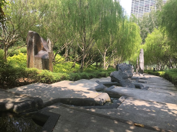 A serene modern garden with natural stone pathways, lush greenery, and elegant seating areas bathed in soft daylight.