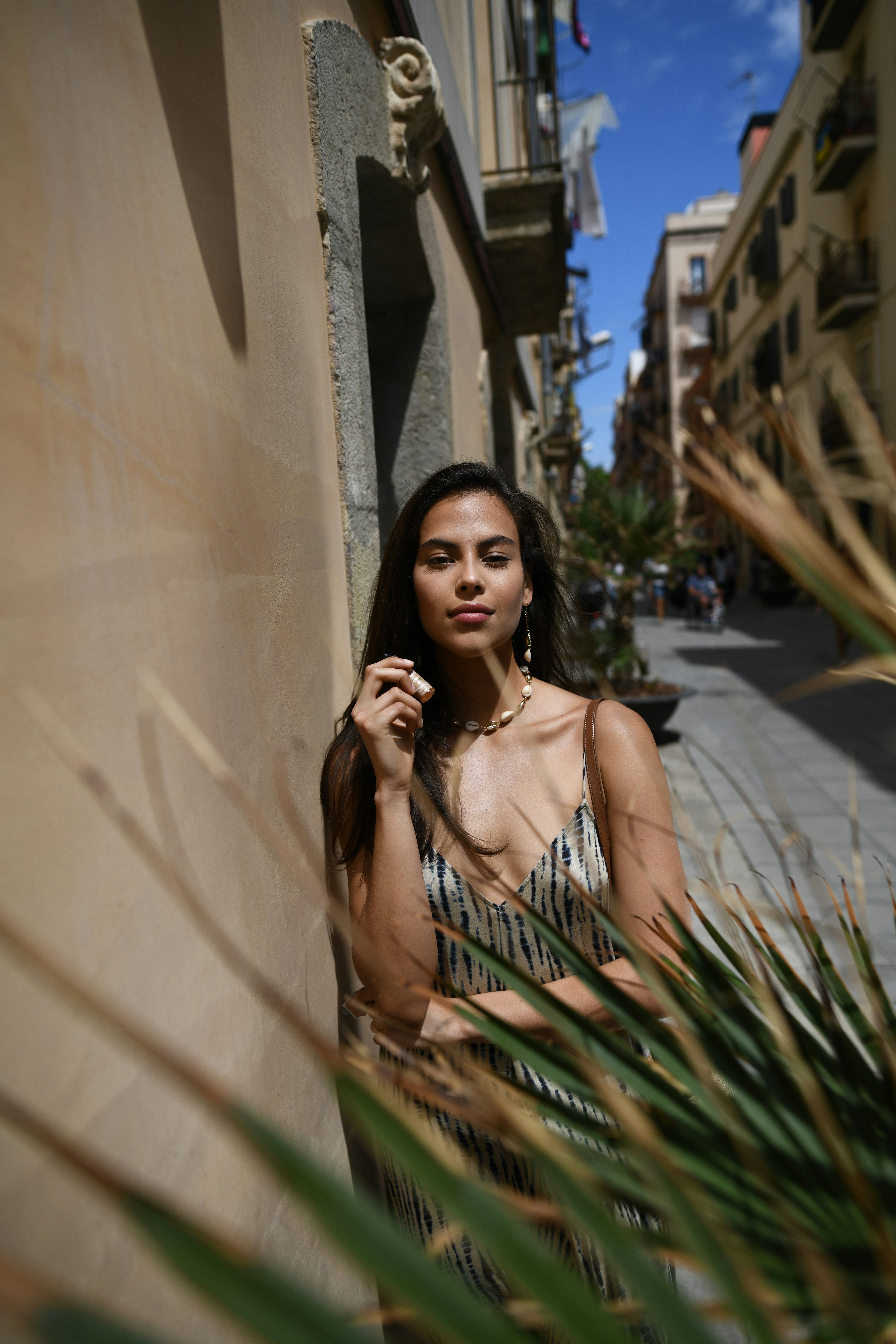 woman leans on wall near plant