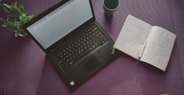 open note book beside black laptop computer