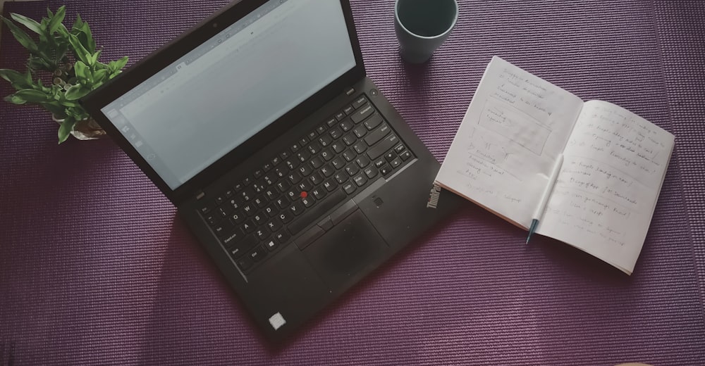 open note book beside black laptop computer