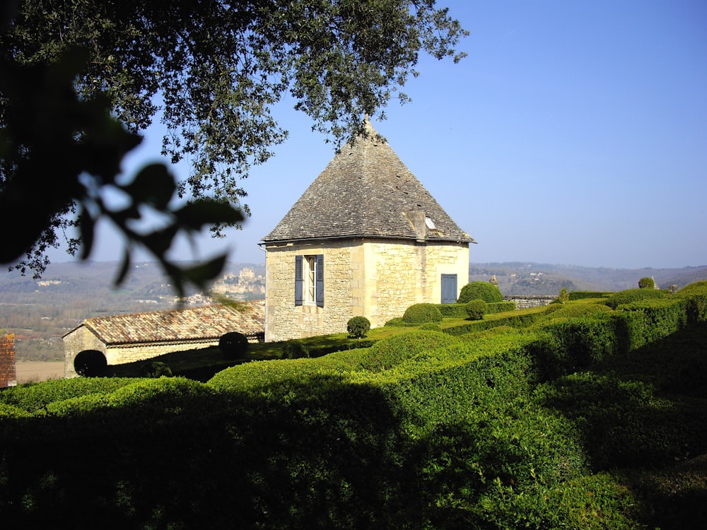 beige concrete mini house in green field viewing mountain during daytime