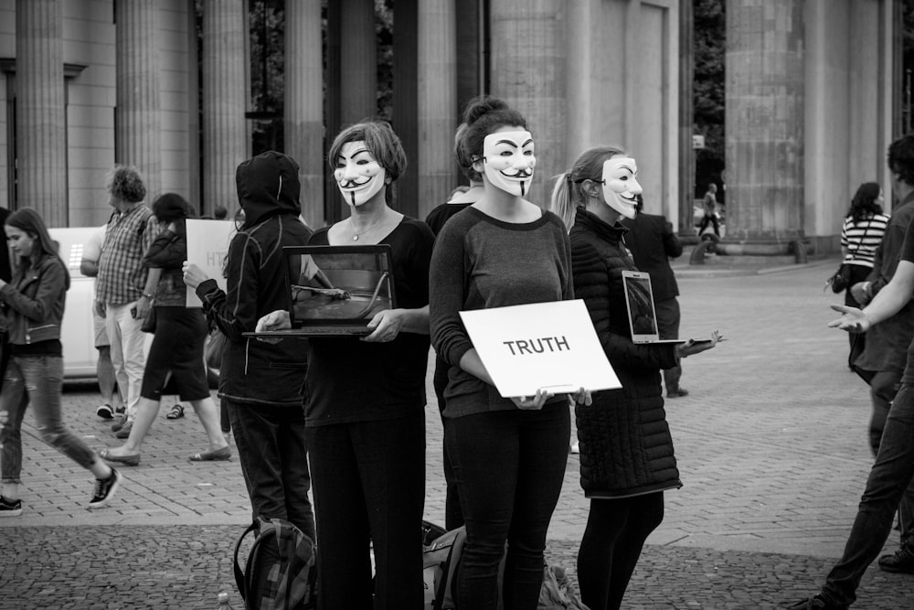 Persone con la maschera con il poster della verità