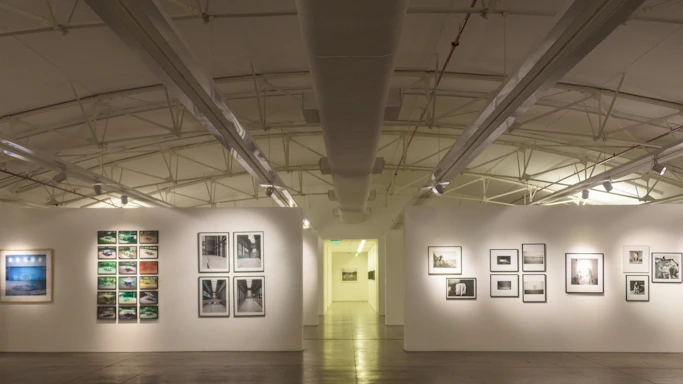 A candid photo of Sam Dicker arranging artwork in a bright, modern gallery space.
