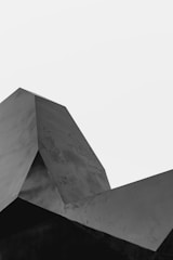 A geometric structure with sharp angles and planes, captured in grayscale against a plain white background.