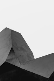 A geometric structure with sharp angles and planes, captured in grayscale against a plain white background.