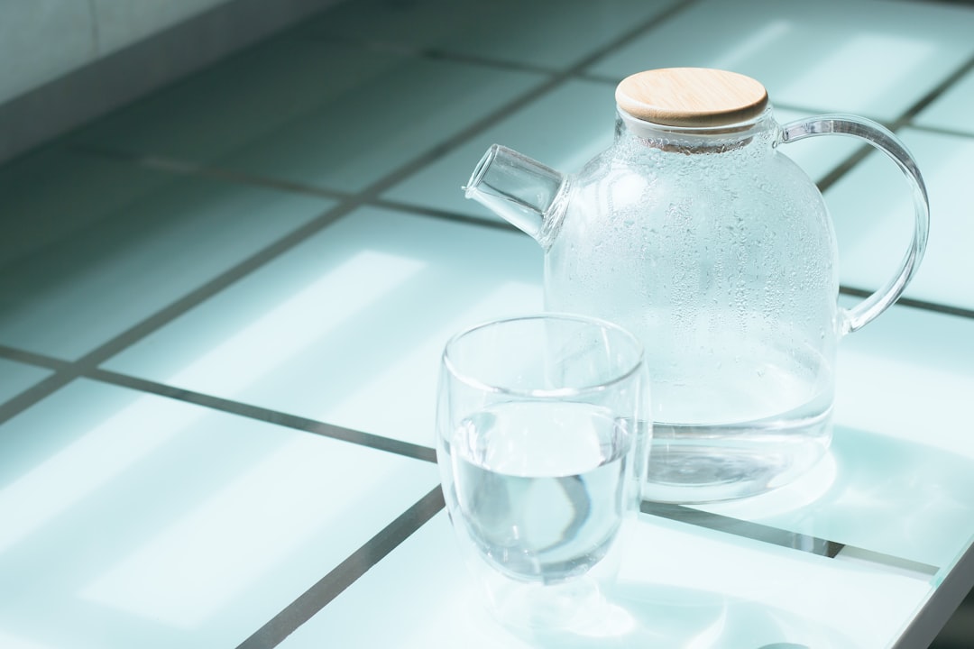 half-filled clear glass cup beside pitcher