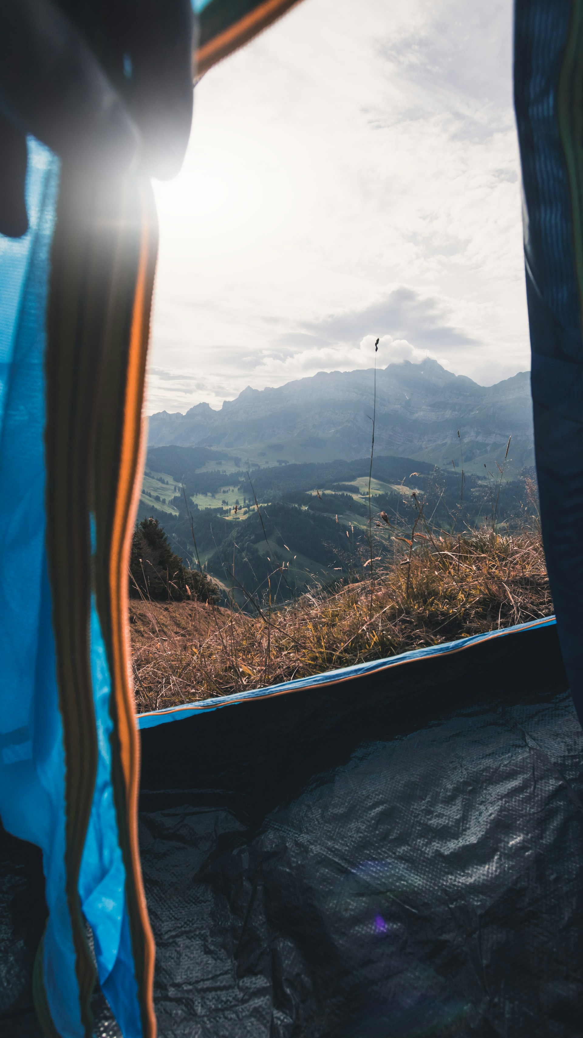 A panoramic view of the lush North Bali mountains from the wooden deck of a luxury tent, bathed in warm earth tones of sunset.