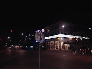 Nighttime shot of illuminated digital signs on electric bikes cruising through city streets, spotlighting dishonest businesses.