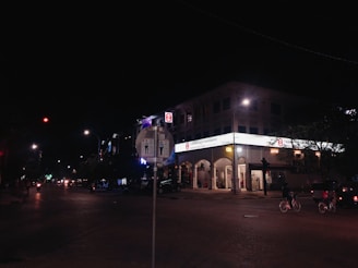 Nighttime shot of illuminated digital signs on electric bikes cruising through city streets, spotlighting dishonest businesses.
