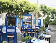 Mediterranean restaurant terrace with rustic wooden tables and bottles of premium Spanish wine.