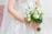 Close-up of a smiling bride holding a bouquet, softly lit with natural light.