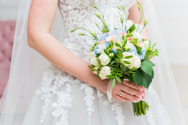 A close-up of a bride's hand holding a delicate bouquet of flowers.