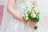 Elegant wedding bouquet with white lilies and greenery held by a bride.