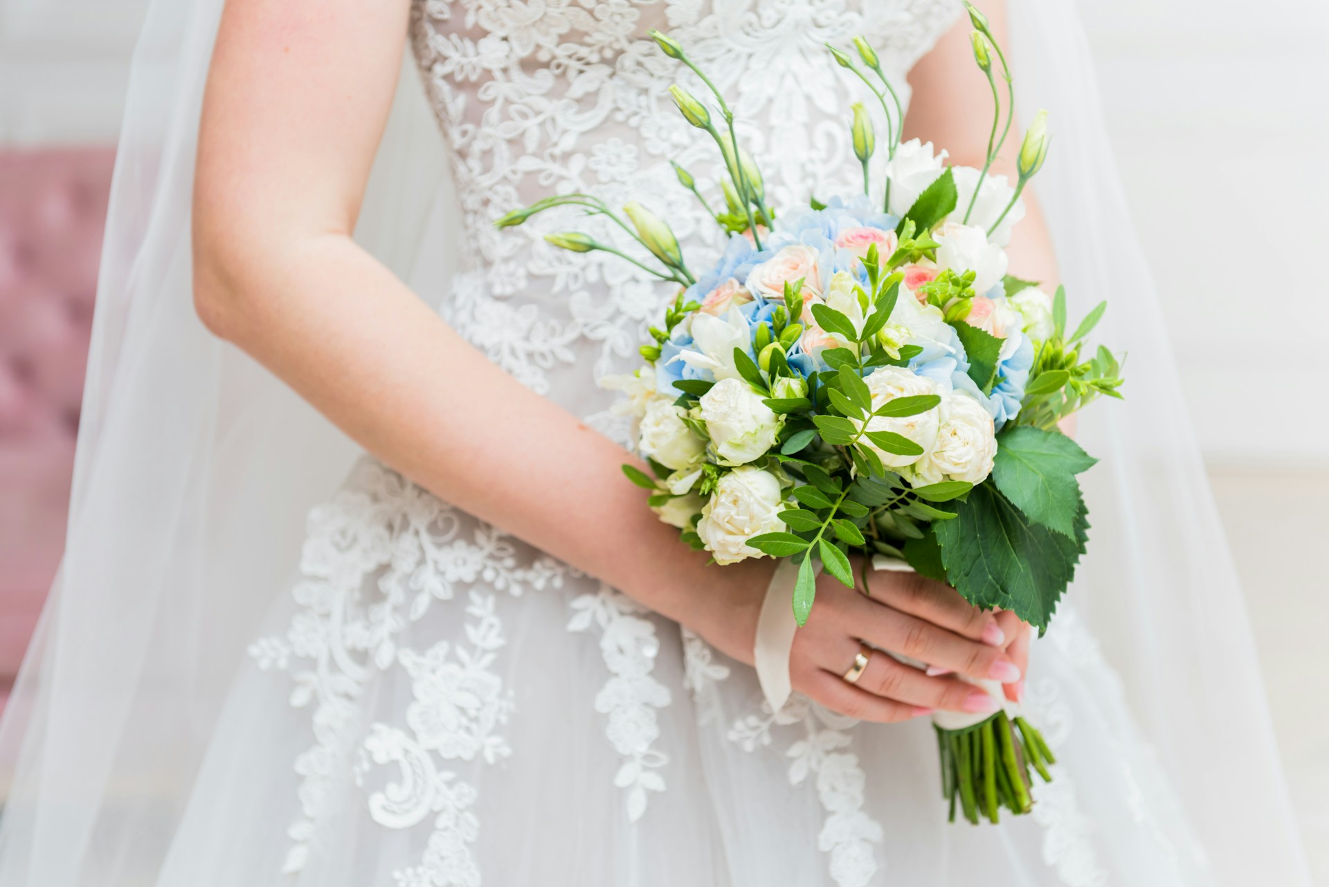 An artistic close-up of a bride’s hands holding a delicate bouquet, showcasing intricate details and subtle shadows.