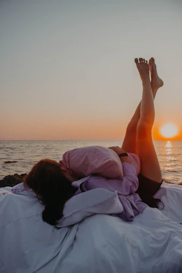 woman lying on white sheets near beach
