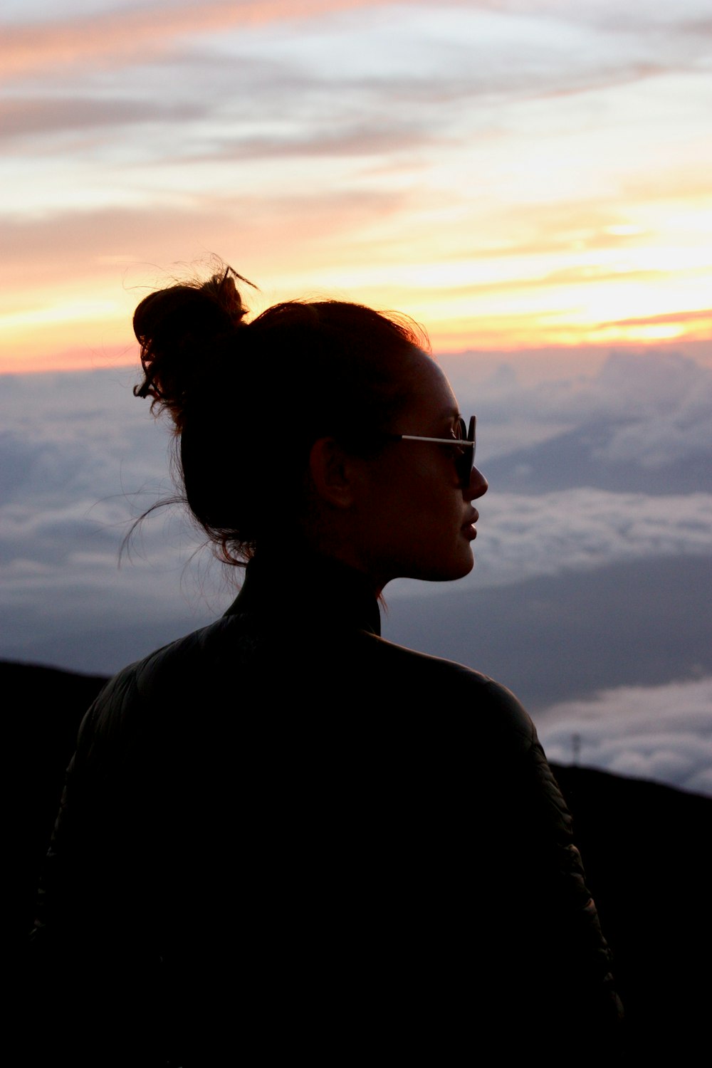 Frau mit Lederjacke und Sonnenbrille über Berge