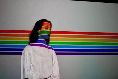 a woman with a rainbow painted face standing in front of a wall