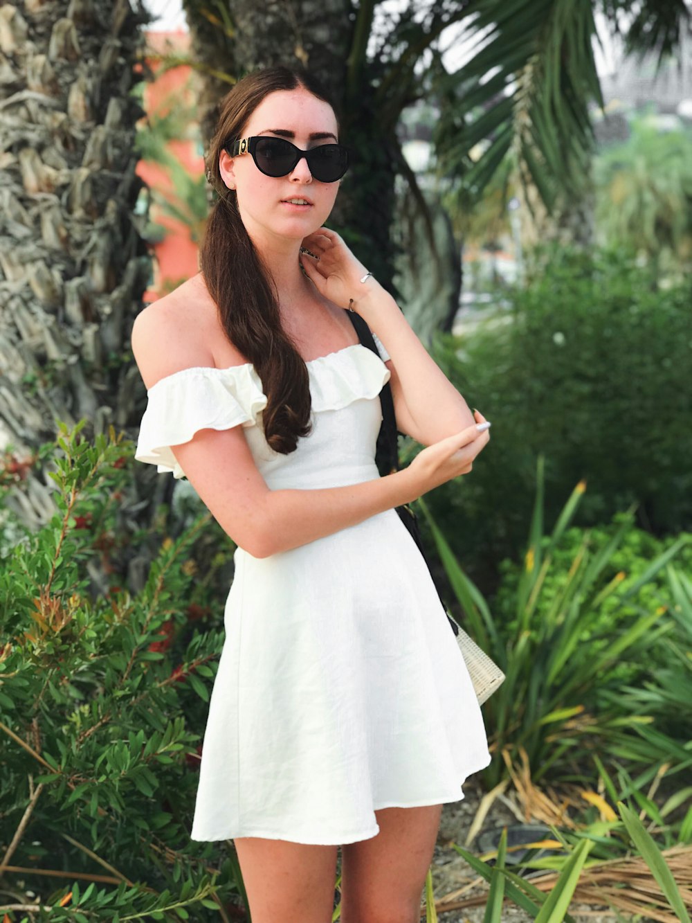 woman in white off-shoulder top beside palm tree