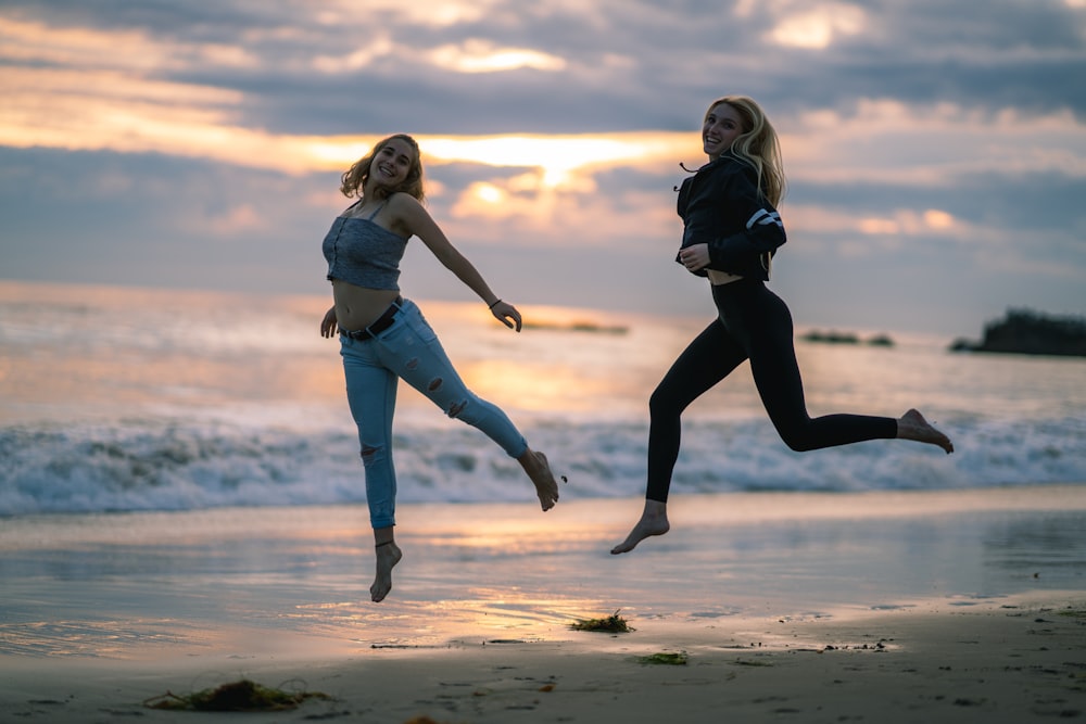 woman wearing blackjacked and black leggings jumping on seashore