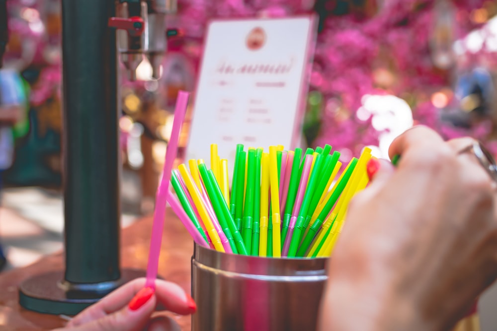 a person holding a cup filled with green and yellow straws