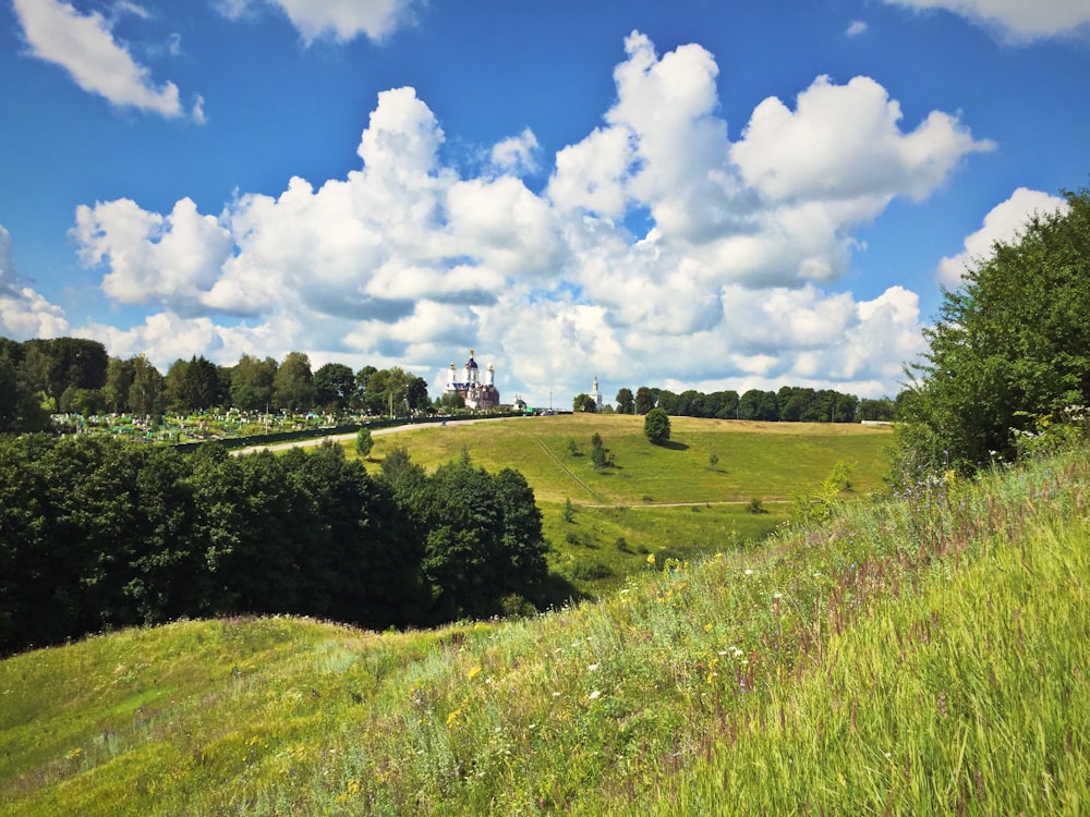 a grassy hill with a church in the distance