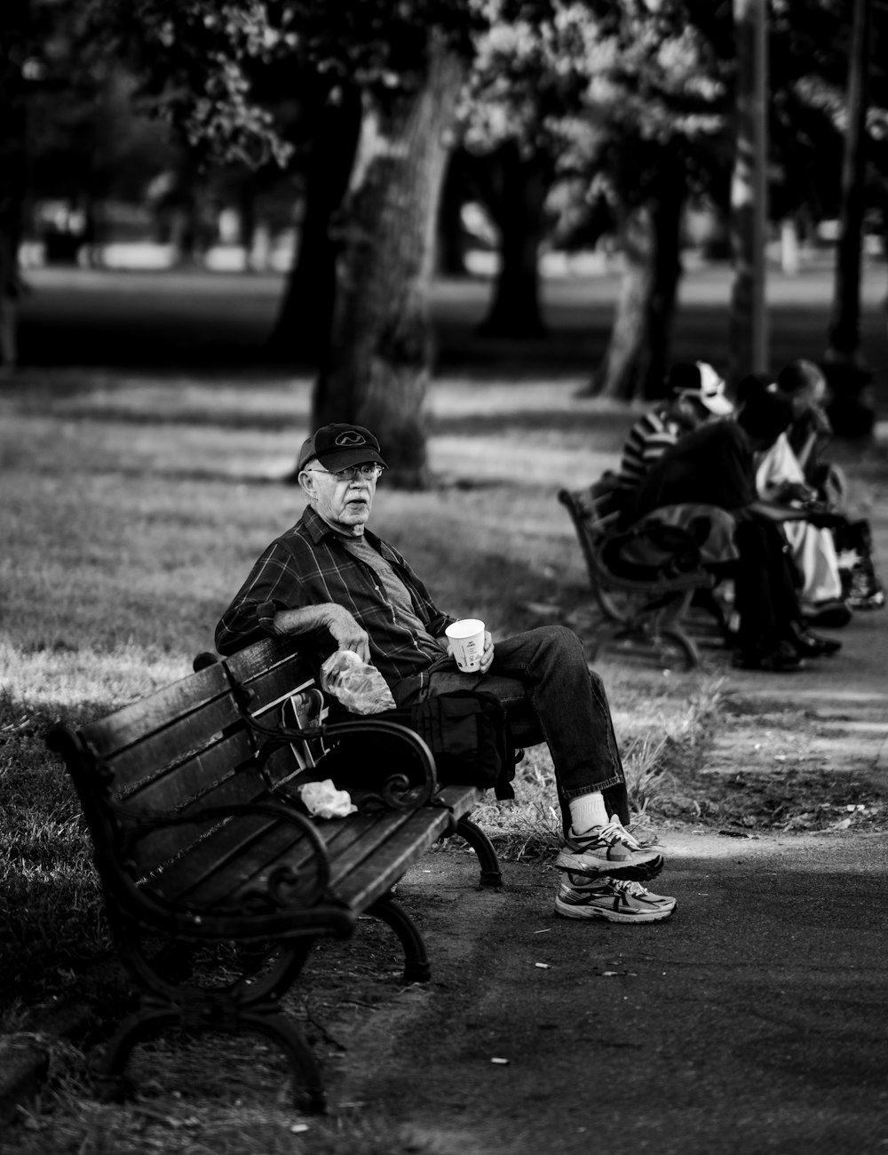 man sitting on bench grayscale photo