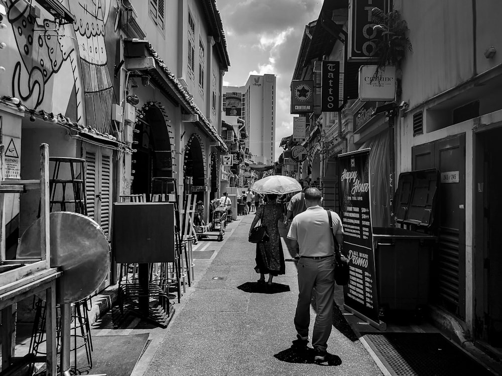 grayscale photography of man and woman walking along narrow pathway