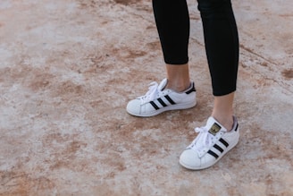 person wearing white-and-black Adidas Superstar sneakers