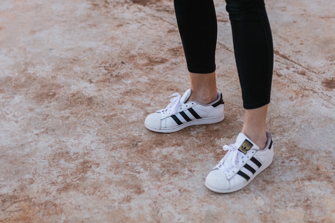 person wearing white-and-black Adidas Superstar sneakers