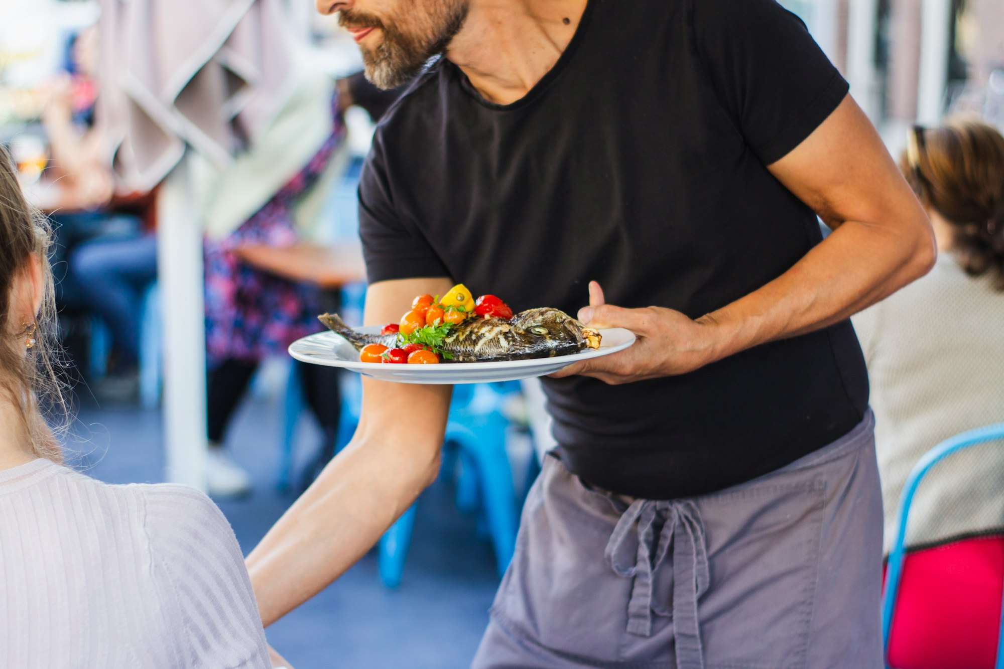 A restaurant server brings guests their food