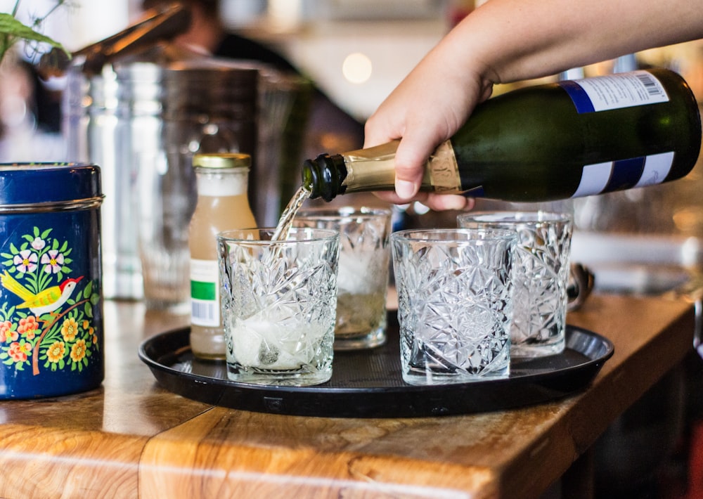 person pouring wine on drinking glasses