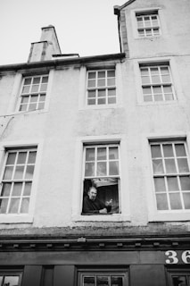 grayscale photo of man on window
