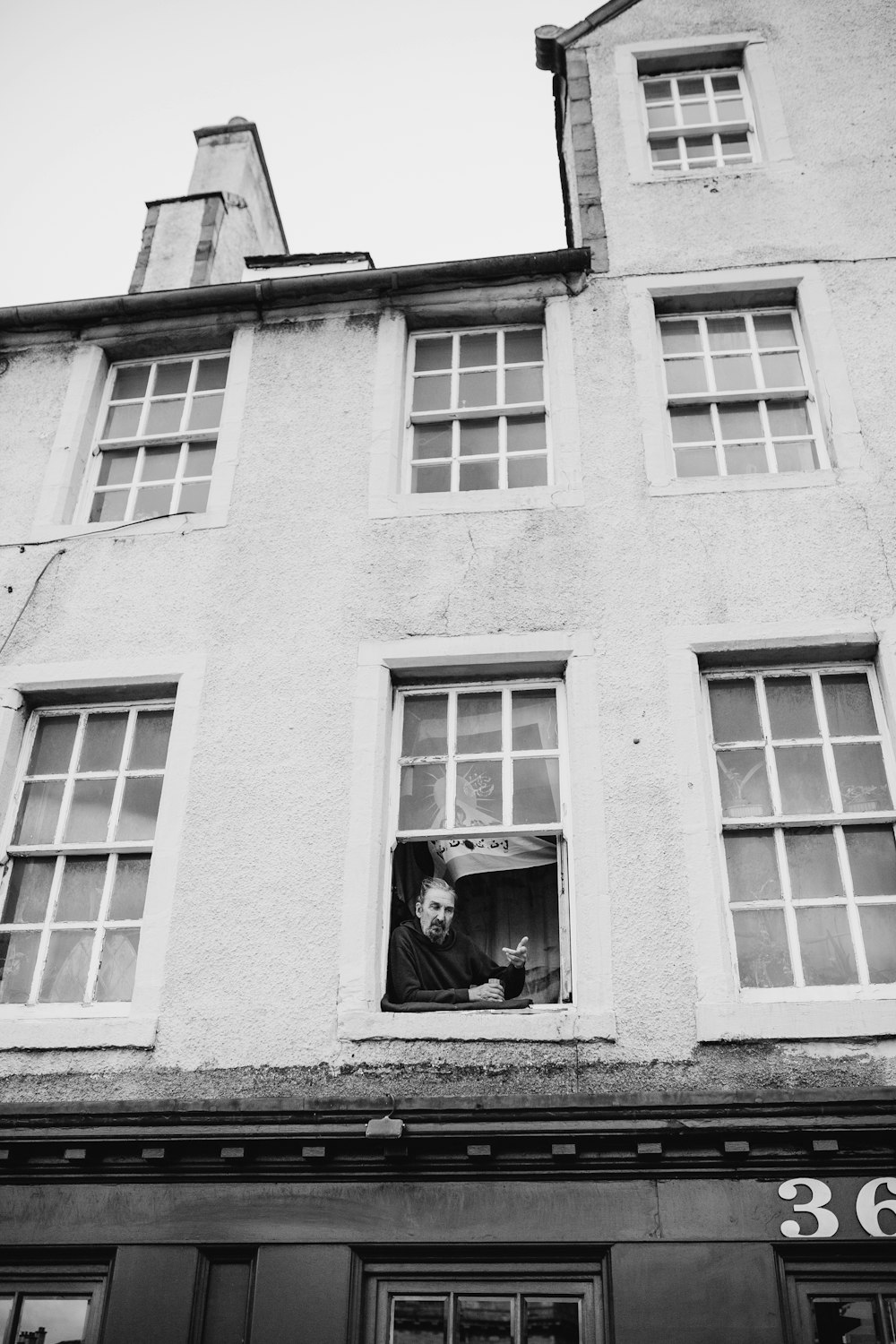 grayscale photo of man on window