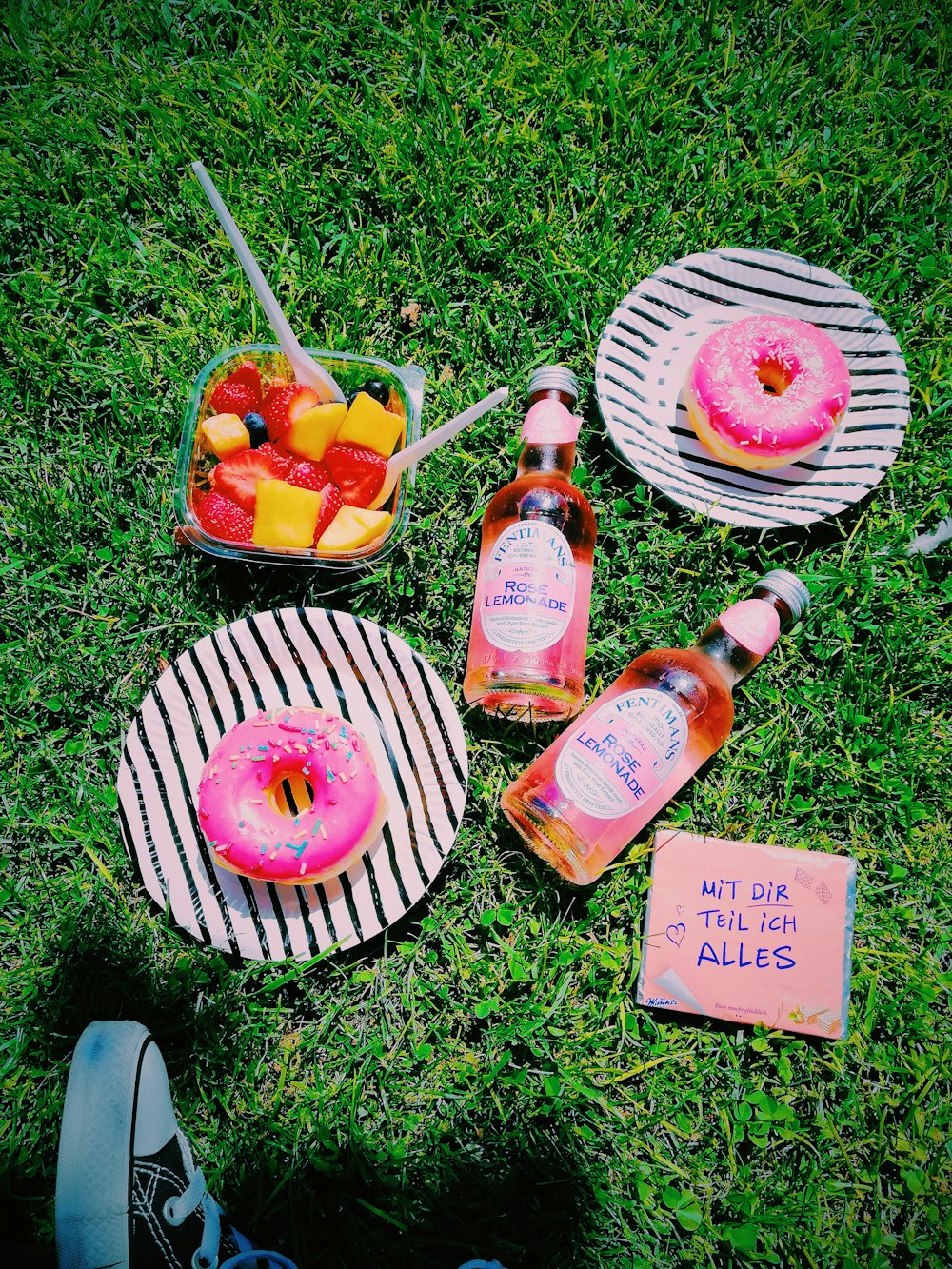 baked donuts on plates near glass bottles on grass