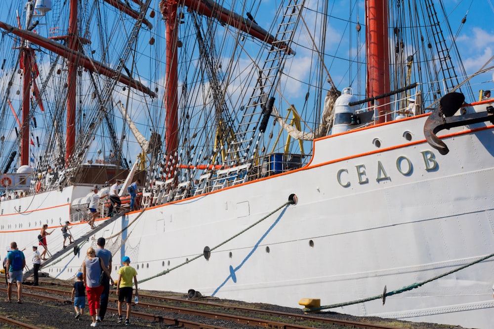 a group of people standing on a train track next to a large ship