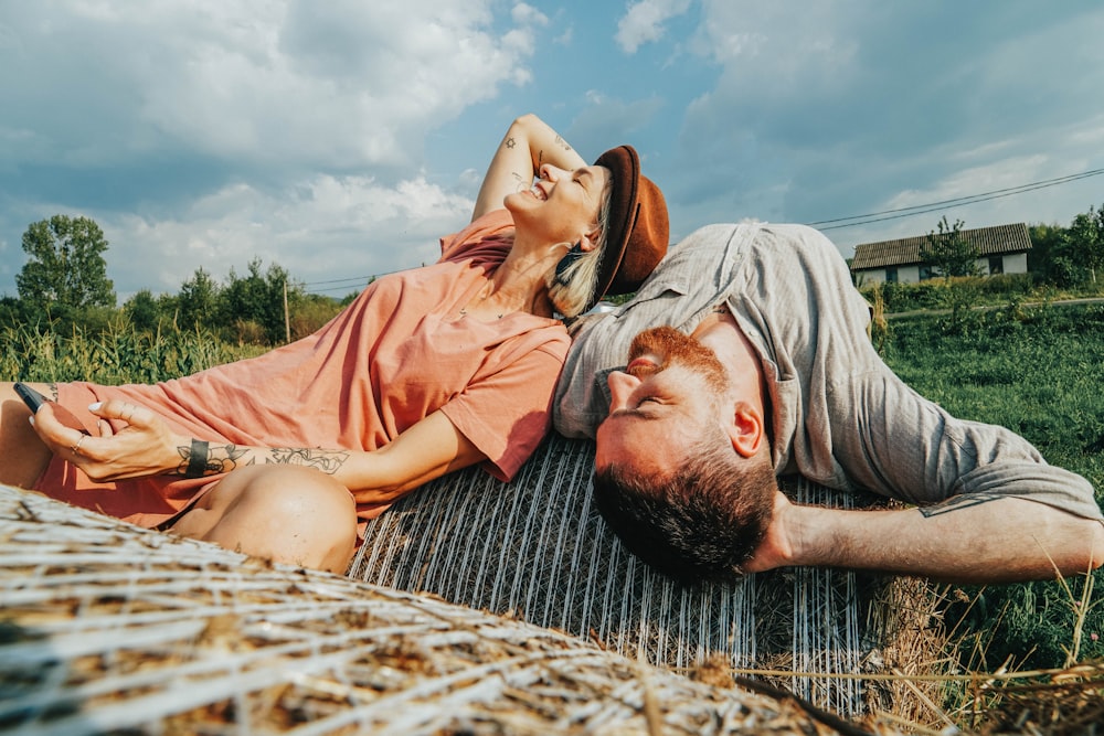 man and woman lying on hay bale during daytime