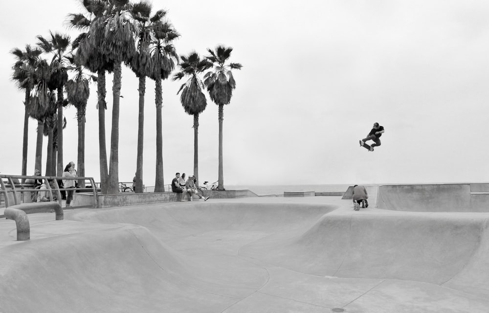 Fotografía en escala de grises de personas en patineta y personas observando