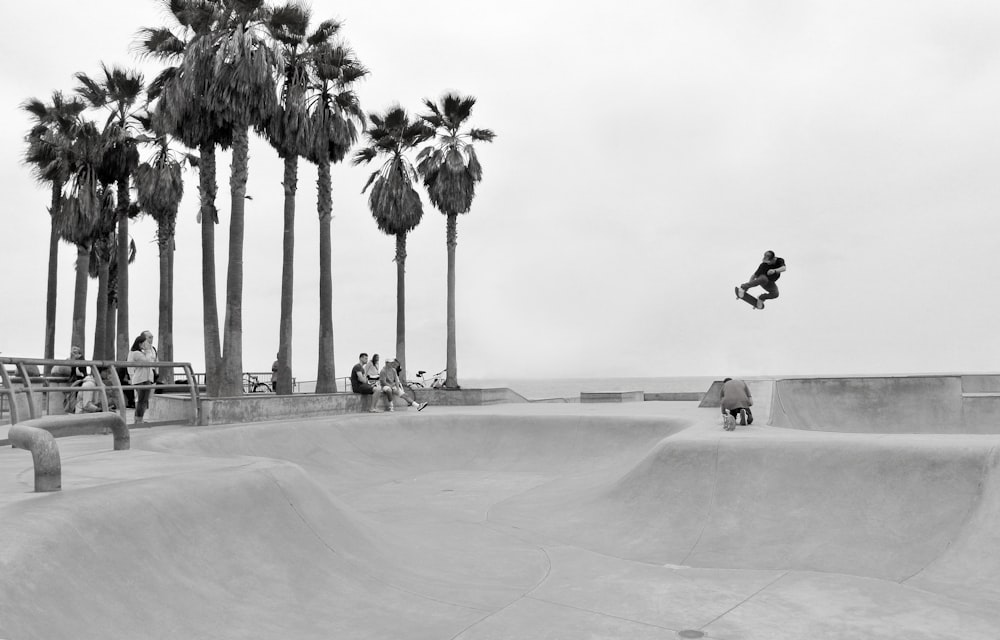grayscale photography of person skateboarding and people watching